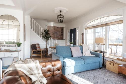 a living room with a blue couch and windows at Marina and Main - In Ground Pool and Games Room in Wellington
