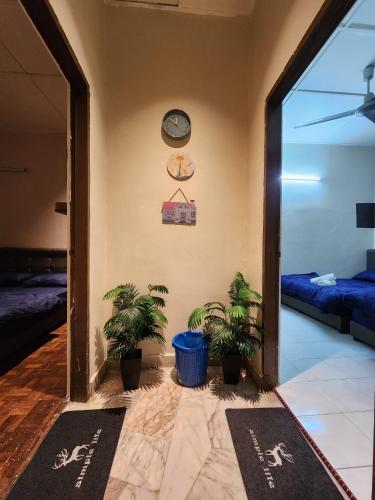 a hallway with potted plants and a clock on the wall at Sun Rock Home by Ipoh Maju Stay in Ipoh