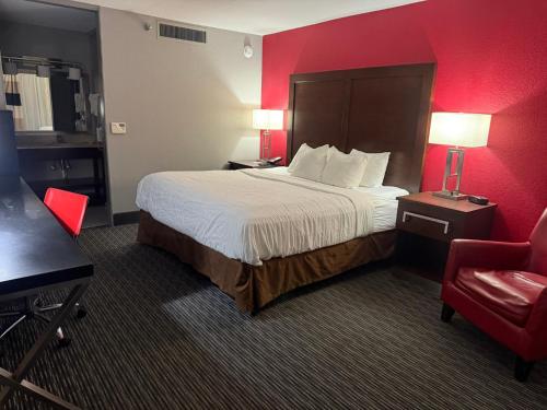 a hotel room with a bed and a red wall at Sonesta Essential - Rapid City in Rapid City