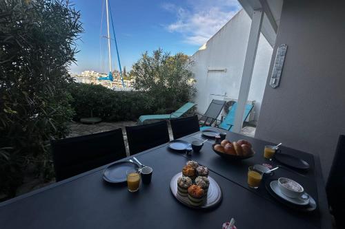 une table noire avec des plaques de nourriture dans l'établissement La Marina de la Petite Caroline vue Port 2 chambres, au Grau-du-Roi
