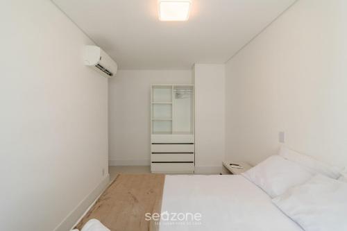 a white room with two beds and a closet at Condomínio a beira-mar c/ piscina - SHC in Piçarras