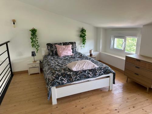 ein Schlafzimmer mit einem Bett mit rosa Kissen darauf in der Unterkunft La Cabane de Nina, cottage chaleureux in Plassac