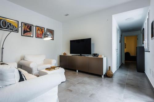 a living room with a white couch and a tv at Oasi Agrumi e Mare in Mascali