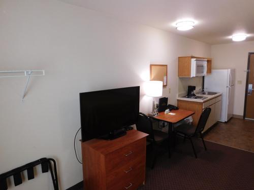 a room with a desk with a television and a kitchen at Birch Hill Suites Rochester - Med City in Rochester