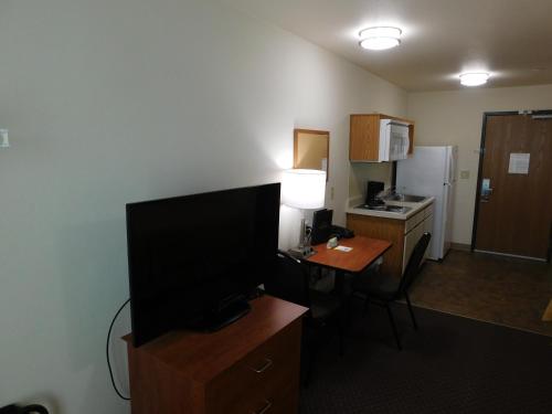 a room with a desk with a television and a kitchen at Birch Hill Suites Rochester - Med City in Rochester