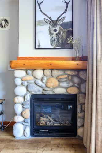 a fireplace with a picture of a deer on the wall at Alpine at The Lodges of Canmore in Canmore
