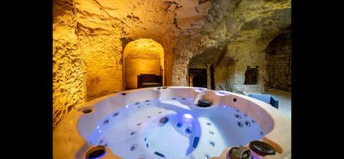 une baignoire dans une grotte avec un mur en pierre dans l'établissement Gîte La Troglo, à Varrains