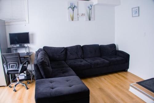 a living room with a black couch and a desk at Cozy Haven 2 bedroom Basement apartment with Treated water in London