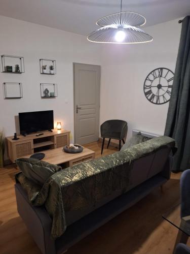 a living room with a couch and a clock on the wall at Victor Hugo - Hyper centre 2 chambres in Saintes