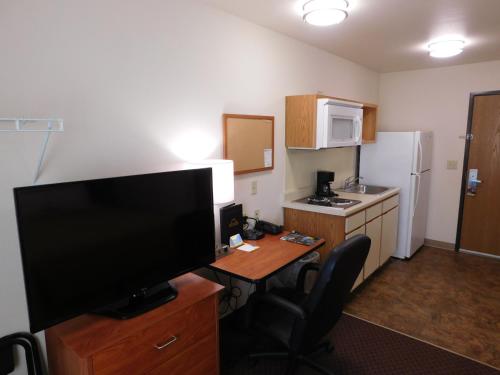 a room with a desk with a television and a kitchen at Birch Hill Suites Rochester - Med City in Rochester
