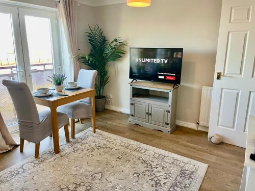 a living room with a television and a table and chairs at Kintyre Apartment in Ayr