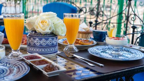 a table with plates of food and glasses of orange juice at Riad Dar El Ouedghiri in Fès