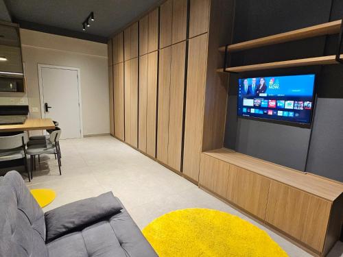 a living room with a couch and a tv on a wall at Lindo AP 2 quartos na Lagoa! in Nova Lima