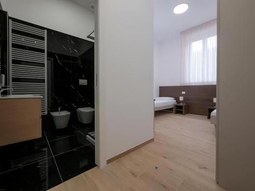 La salle de bains est pourvue de murs noirs et blancs et de parquet. dans l'établissement Casa Sforza Ripamonti Room, à Milan