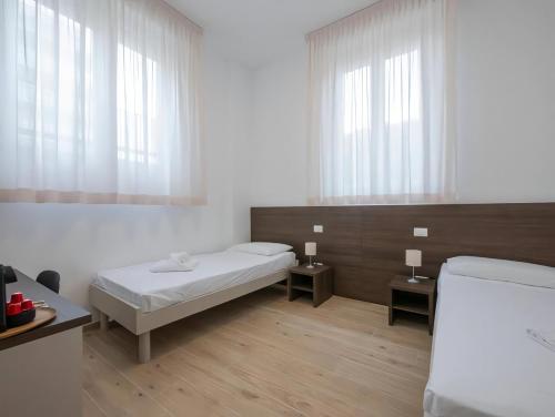 Cette chambre blanche dispose d'un lit et de deux fenêtres. dans l'établissement Casa Sforza Ripamonti Room, à Milan
