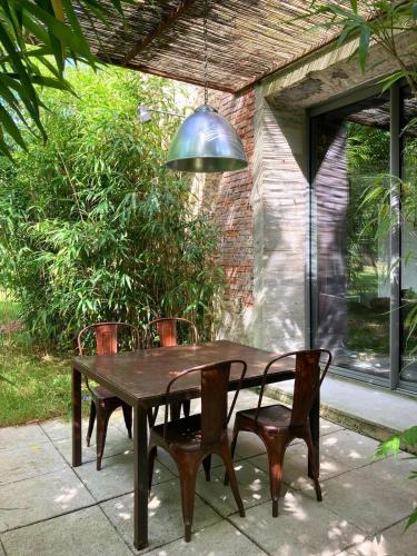 une table en bois avec des chaises et une lampe pendant dans l'établissement Domaine de La Beurrerie, Piscine Naturelle Privée, 5 chambres, Calme absolu, 25mn du PUY DuFou, 2 Logements attenants pour votre Confort, à Saint-Mesmin