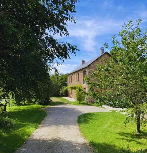 un chemin de terre menant à un grand bâtiment en briques dans l'établissement Domaine de La Beurrerie, Piscine Naturelle Privée, 5 chambres, Calme absolu, 25mn du PUY DuFou, 2 Logements attenants pour votre Confort, à Saint-Mesmin