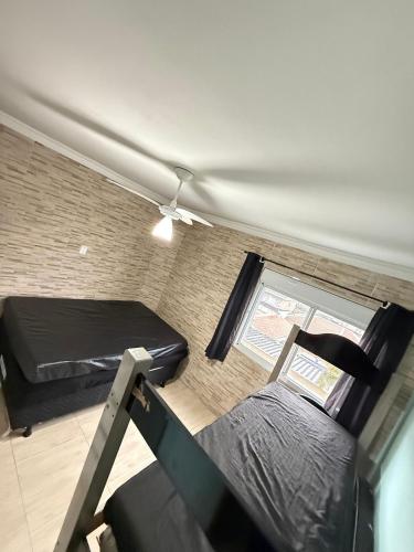 a small room with a bed and a window at Pé na areia canto do forte II in Praia Grande