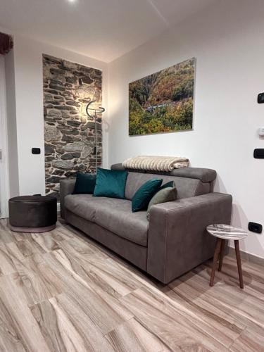 a living room with a couch and a stone wall at Lakes and Mountains Magic Holiday House in Omegna