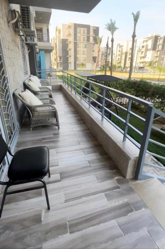 a chair sitting on a balcony with benches at Luxury apartment with garden in Janna 2 sheikh Zayed in Sheikh Zayed