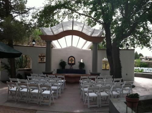 a set up for a wedding in a courtyard with white chairs at Lundeen Inn of the Arts in Las Cruces