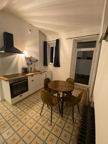 une cuisine avec une table et des chaises dans une pièce dans l'établissement L'Imprimerie A3, studio cosy au cœur de La Roche !, à La Roche-sur-Yon