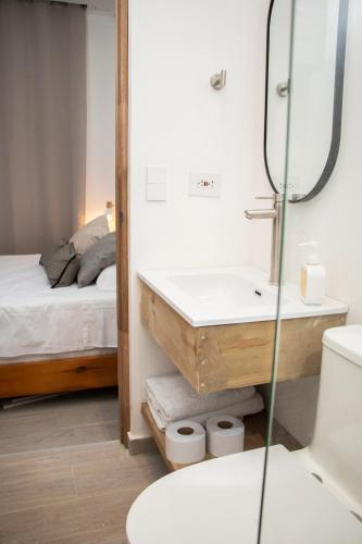 a bathroom with a sink and a mirror and a bed at Zenia 70 Living & Suites in Medellín