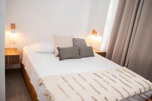 a bedroom with a white bed with two pillows on it at Zenia 70 Living & Suites in Medellín