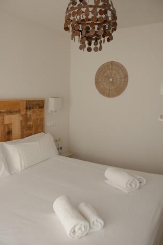 a bedroom with a white bed with two towels on it at Hostal La Torre Ibiza Cap Negret in San Antonio