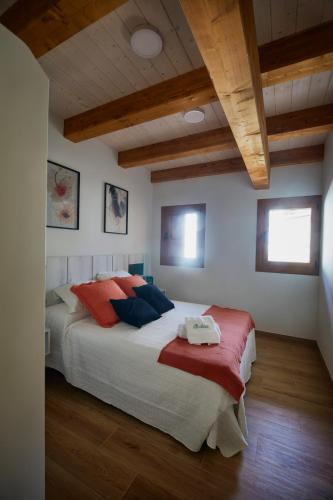 a bedroom with a large bed with red and blue pillows at Apartamentos Rurales Balisa in Esparza