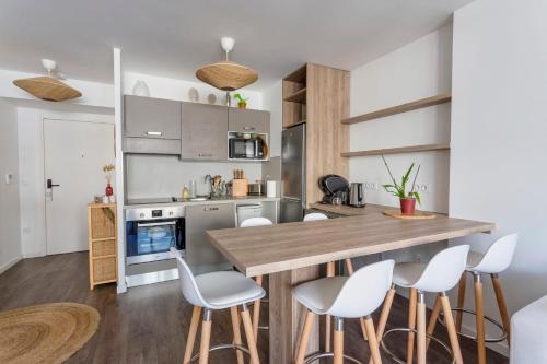 - une cuisine avec une table en bois et des chaises blanches dans l'établissement Saint-Ouen - Simone Veil 1bdr by B'Your Home, à Saint-Ouen