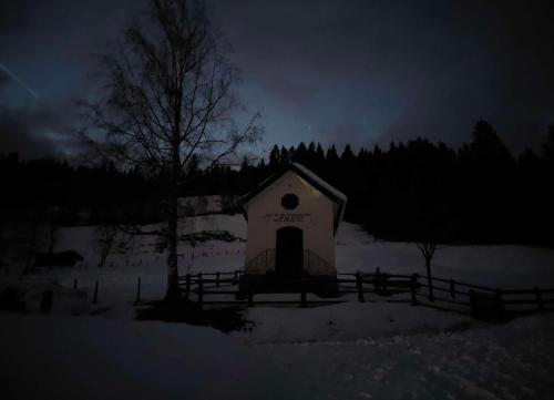 a small white building in a snowy field at night at Bauernhof Unterbichl in Flachau