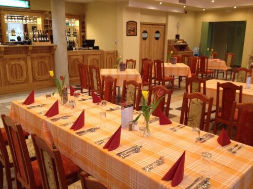 a dining room with tables and chairs with red napkins at Aranytál Panzió in Komárom