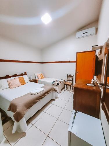 a hotel room with two beds and a desk and a desk at Suítes da Penha in Capitólio