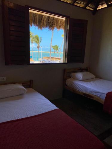 two beds in a room with a view of the beach at Pousada Bate Vento in Itarema