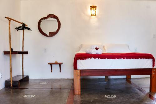 a bedroom with a bed with a red blanket and a mirror at Pousada Bate Vento in Itarema