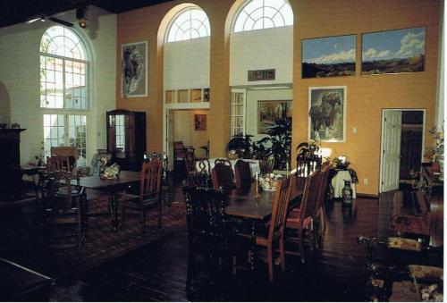 un comedor con mesas, sillas y ventanas en Lundeen Inn of the Arts en Las Cruces