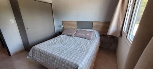 Un dormitorio pequeño con una cama y una ventana. en Blue House 6 Villa La Angostura, en Villa La Angostura