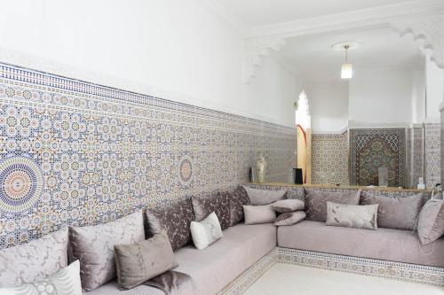 a living room with a couch and a wall with tiles at Dar Al Hajja Fatima in Rabat