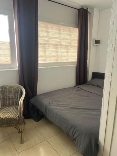 a bedroom with a bed and a chair and a window at Room with bathroom and kitchen in Sant Josep de Sa Talaia