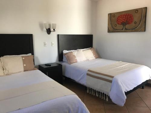 a hotel room with two beds and a picture on the wall at Hotel Finca Las Hortensias in Tepotzotlán