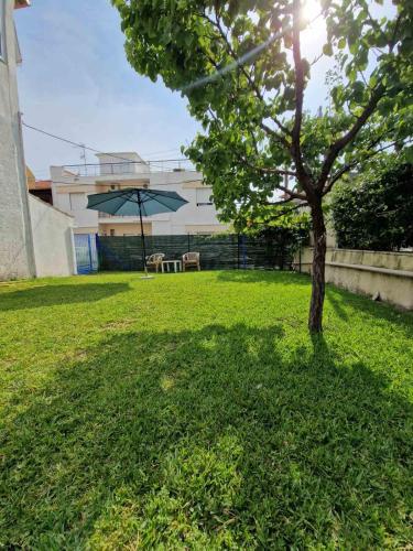 a tree in a yard with a building and an umbrella at Seaside Apartment in Vergia in Vergia