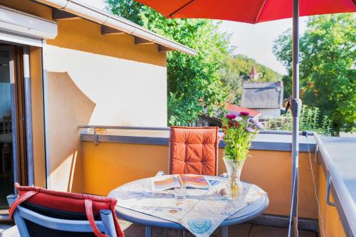 a table with a vase of flowers on a balcony with an umbrella at Fewo am Strand in Koserow - Casa del Mar - 42m bis zum Strand in Ostseebad Koserow