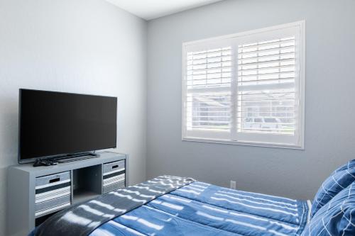 a bedroom with a flat screen tv and a bed at Spacious 4BR Home With BBQ, Near Sequoia & Fresno in Hanford