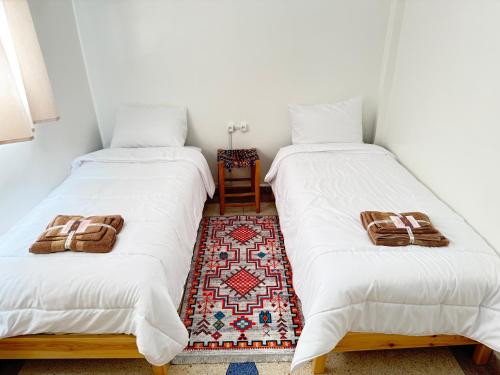 two twin beds in a room with a table at Orange Surf House in Agadir