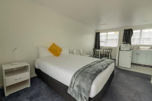 a bedroom with a large bed and a kitchen at Marton Motel NZ in Marton