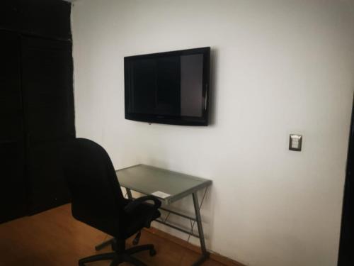 a desk with a chair and a tv on a wall at Rooms & suites in Monterrey