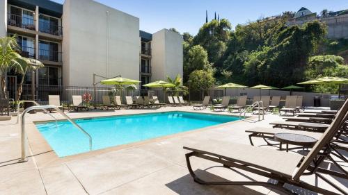 a pool with chairs and umbrellas next to a hotel at Style, Peace, Comfort in N Hollywood Next to Burbank Free Indoor Parking and Wifi in Burbank