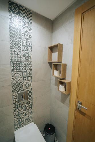 a bathroom with a toilet and a tile wall at Emplacement Central Lumineux & Chic Prés de Station Tramway KFC Et Carrefour Abdelmoumen Et 2 Mars Casablanca in Casablanca