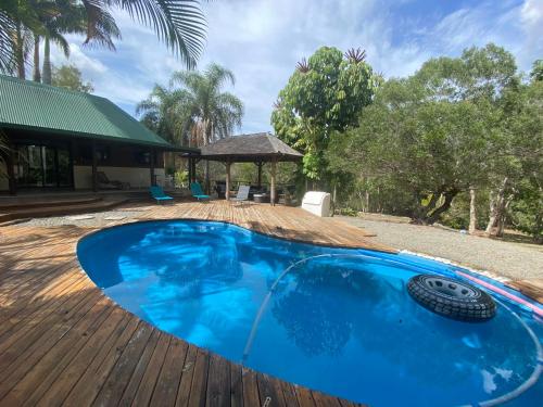 a large blue swimming pool on a wooden deck at L'allée des Pins in Païta